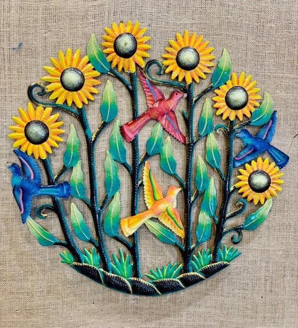 A round painted metal wall hanging of sunflowers and birds