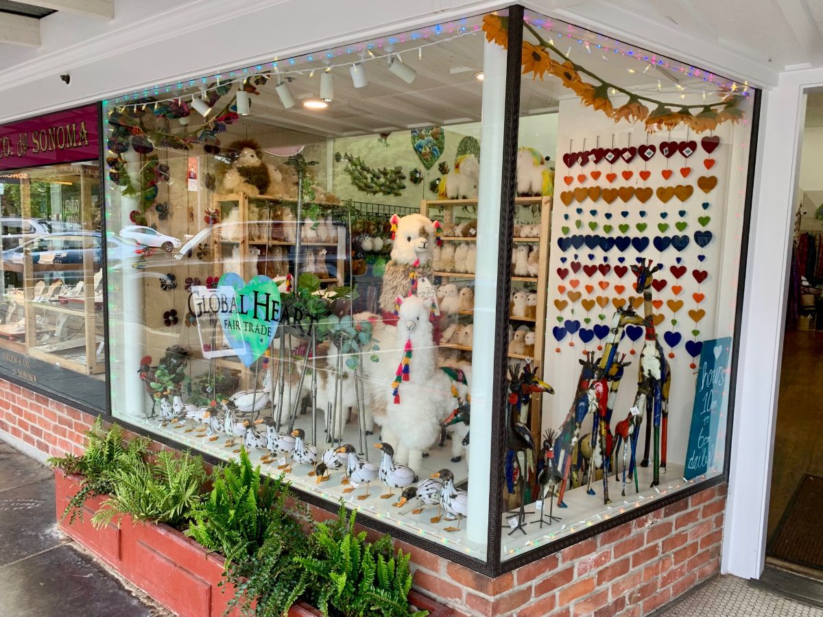 The shop window at 498 First Street East: alpaca and bird figures, a wall of small painted hearts and the heart logo on the glass, over a brick planter of ferns
